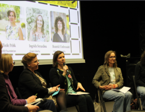 Panelists discuss during the event, with dark background and microphone